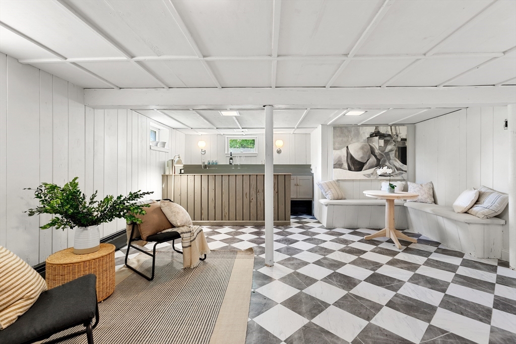 Basement lounge with a small bar, built-in bench seating, and a black-and-white checkerboard floor.