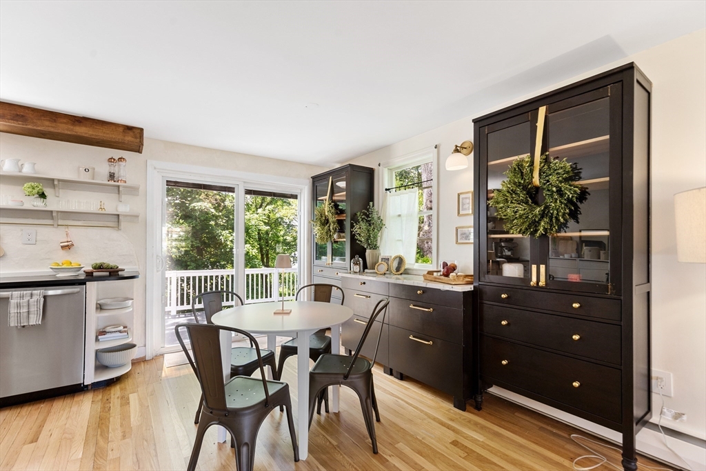 Kitchen and dining area with dark cabinets, a round table, and glass doors to a leafy deck.