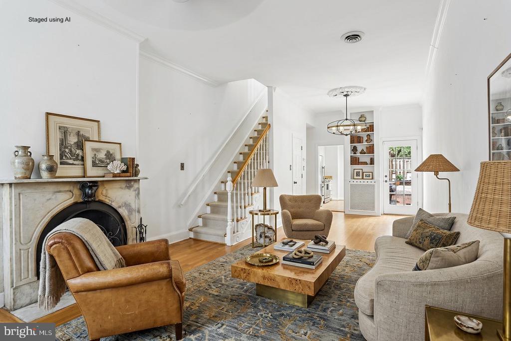Living room with a marble fireplace, staircase, and neutral seating around a coffee table.