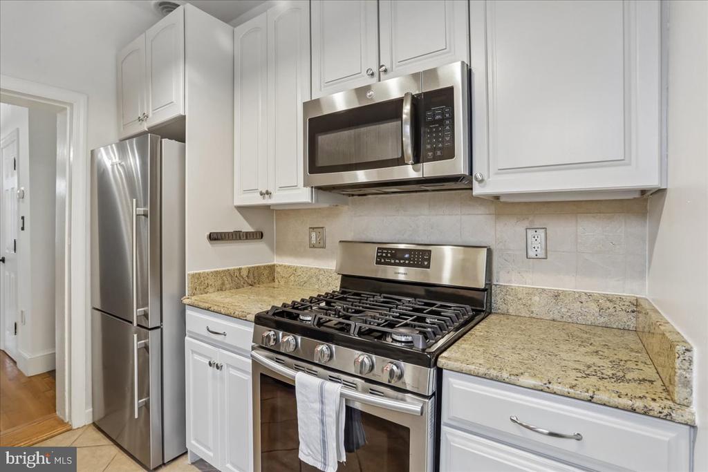 Kitchen with white cabinets, granite counters, stainless steel appliances, and a gas range.