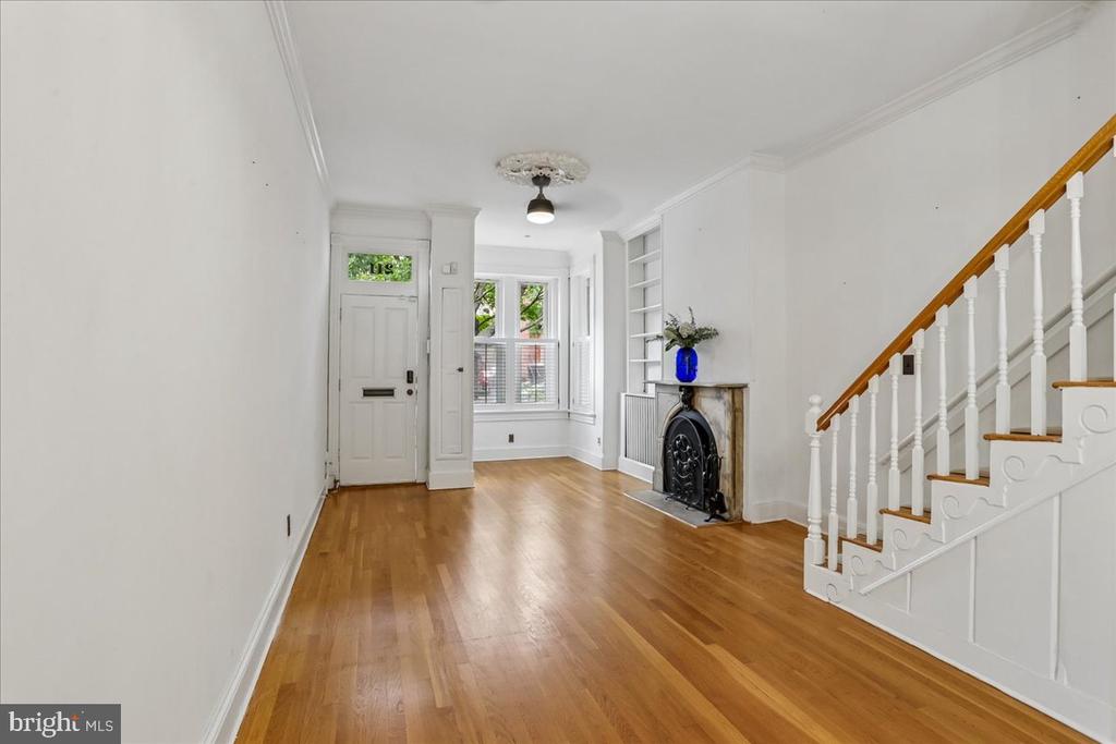 Front living room with hardwood floors, a decorative fireplace, bay window, and staircase.