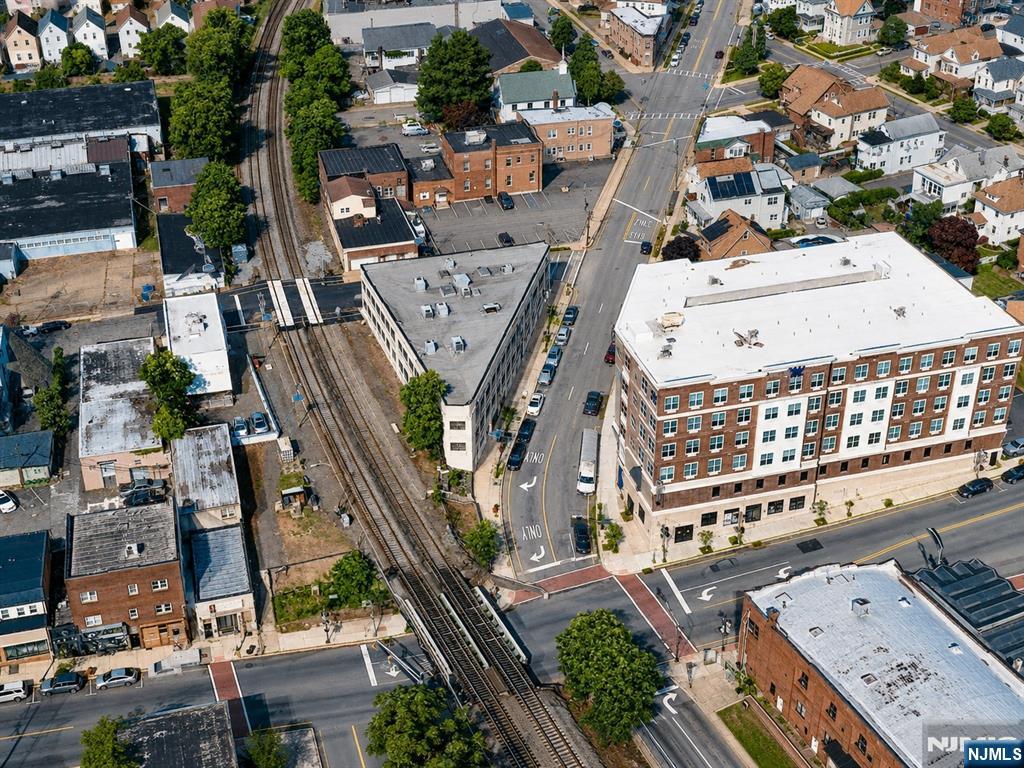 Aerial view of a large brick building beside railroad tracks and a busy intersection.
