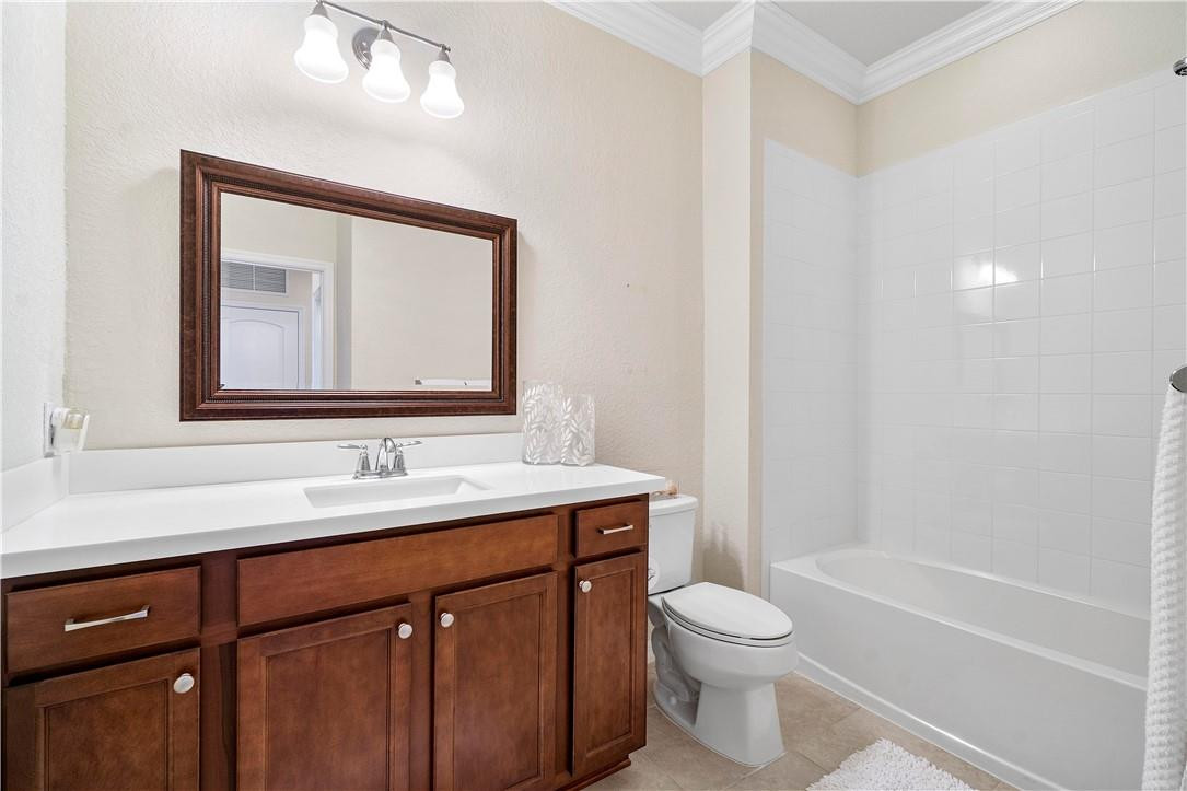 Bathroom with a dark wood vanity, framed mirror, and white tub-shower.