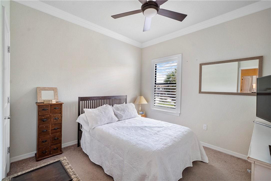 Bedroom with white bedding, a dark wood bed frame, and a louvered window.