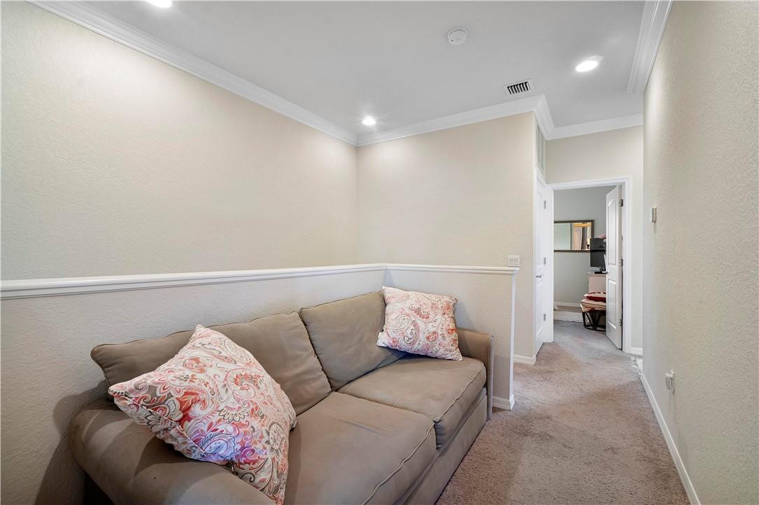 Furnished sitting room with a taupe sofa and patterned pillows beside an open doorway.