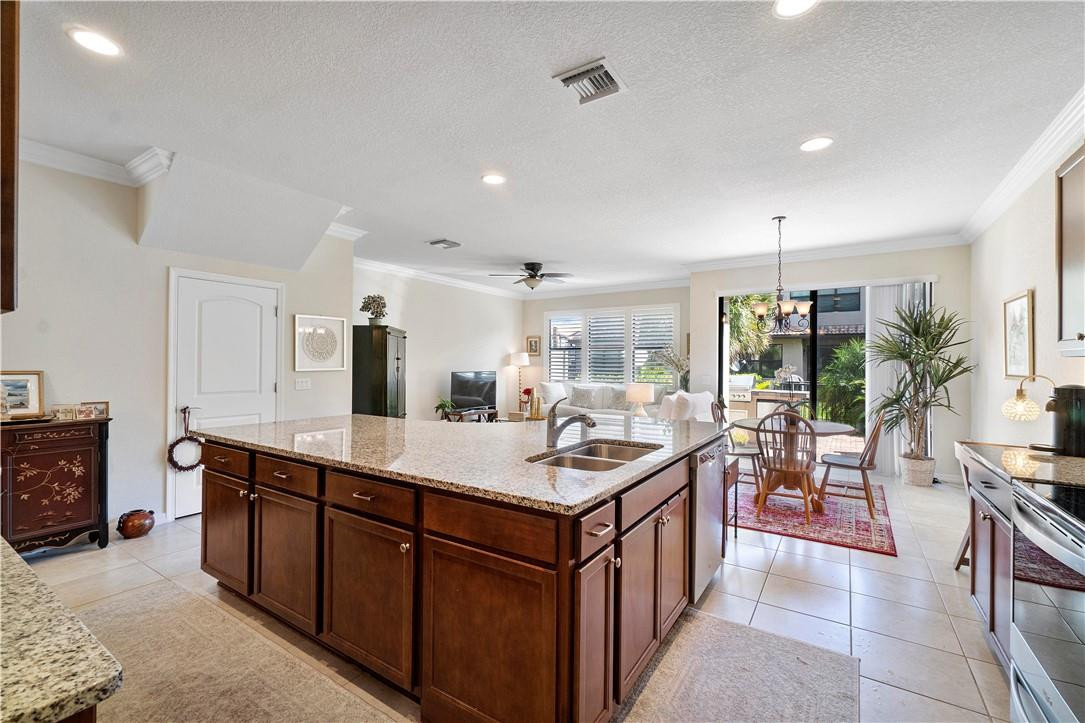Open-plan kitchen with a large granite island, dark wood cabinets, and sliding doors to a patio.