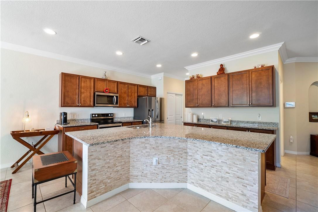 Kitchen with a large stone-topped island, dark wood cabinets, and stainless steel appliances.