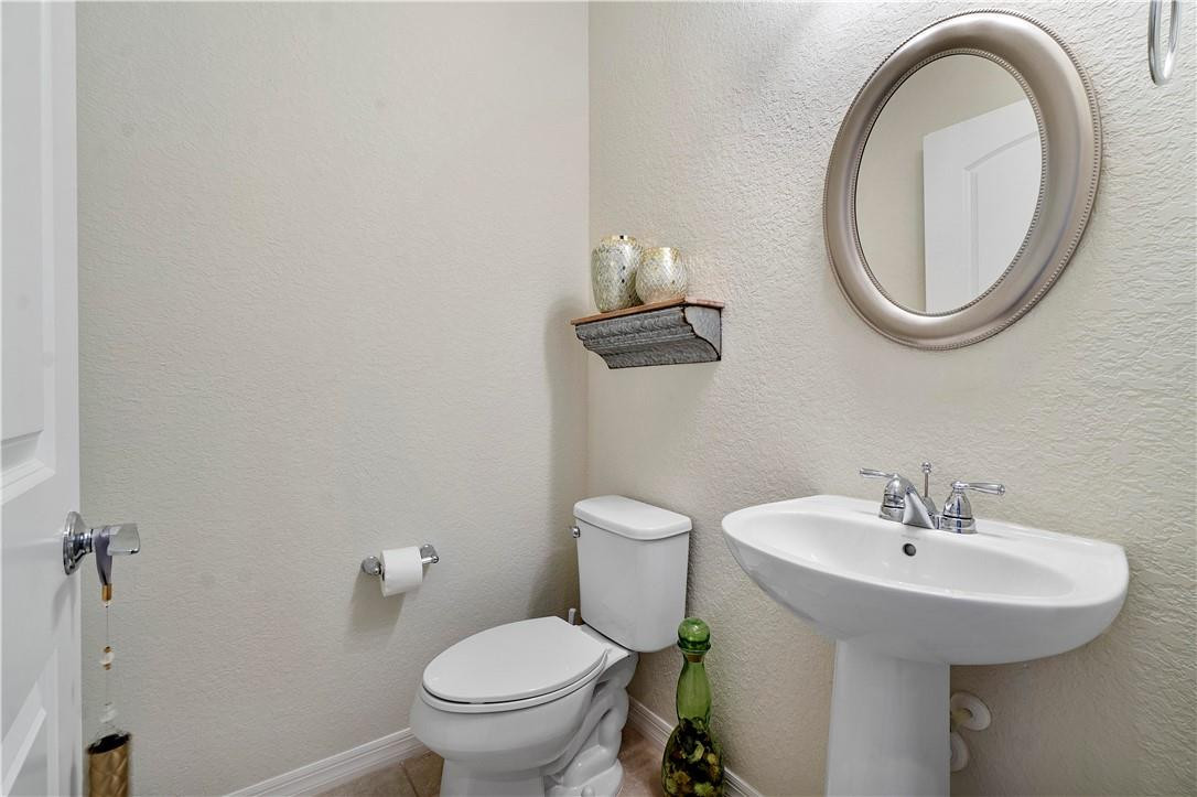 Bathroom with a white pedestal sink, toilet, and large oval mirror.