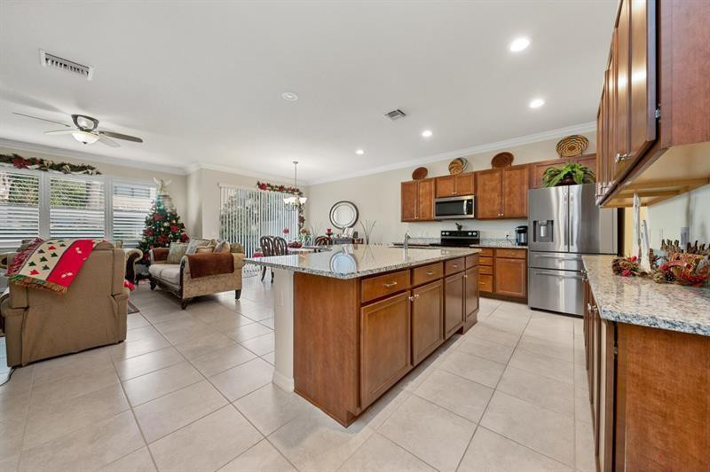 Open-plan kitchen with a granite island and wood cabinetry beside a living room decorated for Christmas.