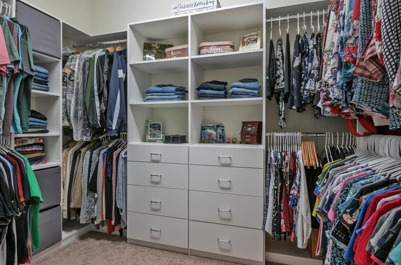 Walk-in closet with built-in drawers, open shelves, and clothes hanging on three sides.