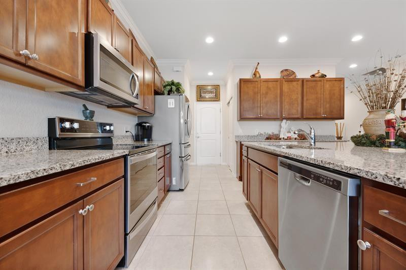 Kitchen with warm wood cabinets, granite counters, and stainless steel appliances.