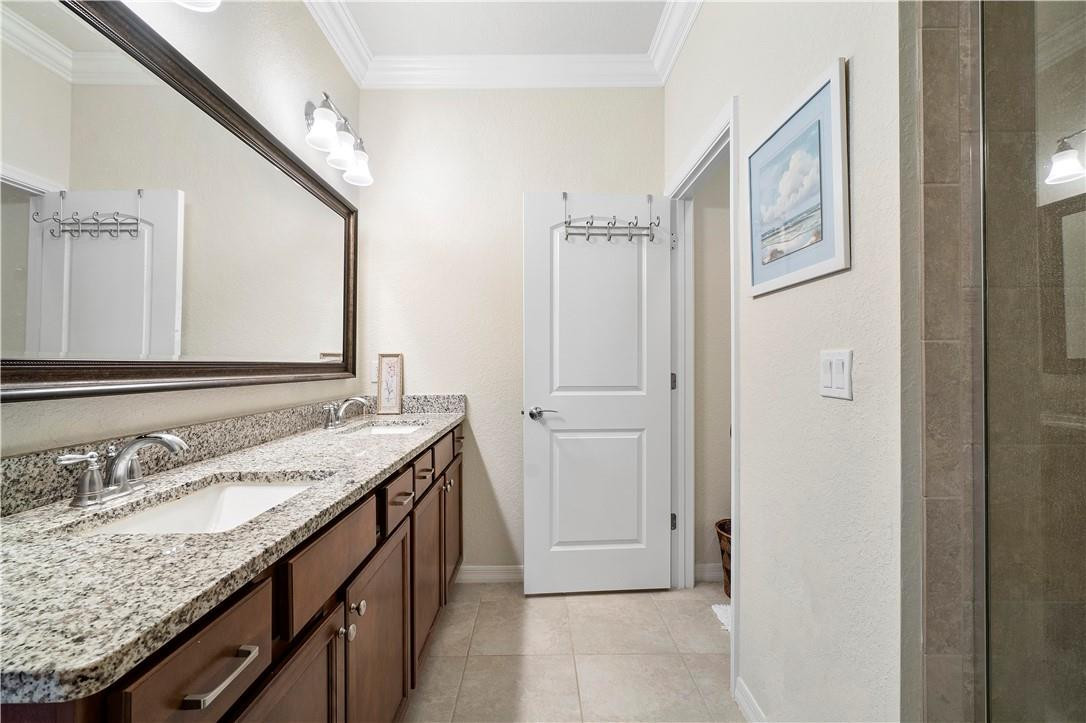 Bathroom with a double-sink granite vanity, dark wood cabinets, and a large framed mirror.
