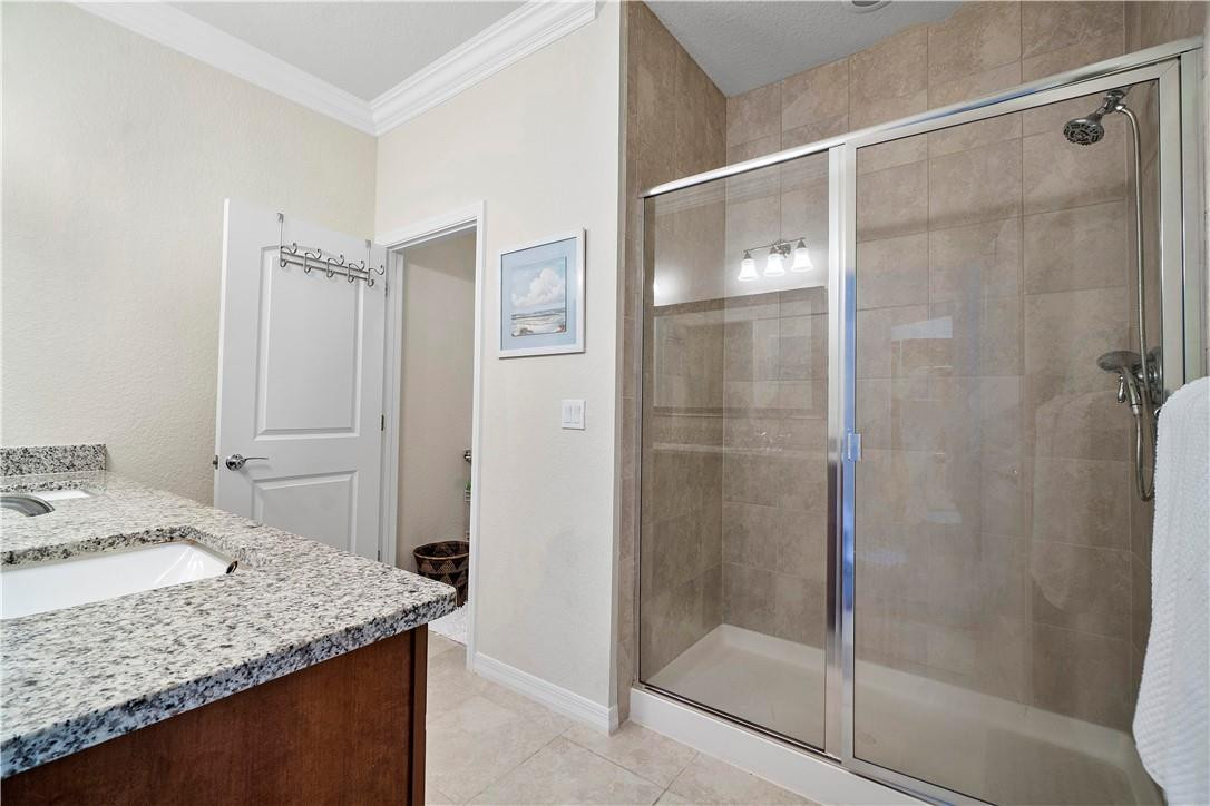 Bathroom with a granite vanity and spacious glass-enclosed tiled shower.