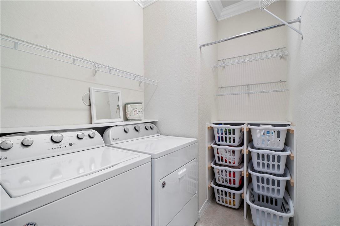 Laundry room with white washer and dryer, wire shelving, and stacked laundry baskets.