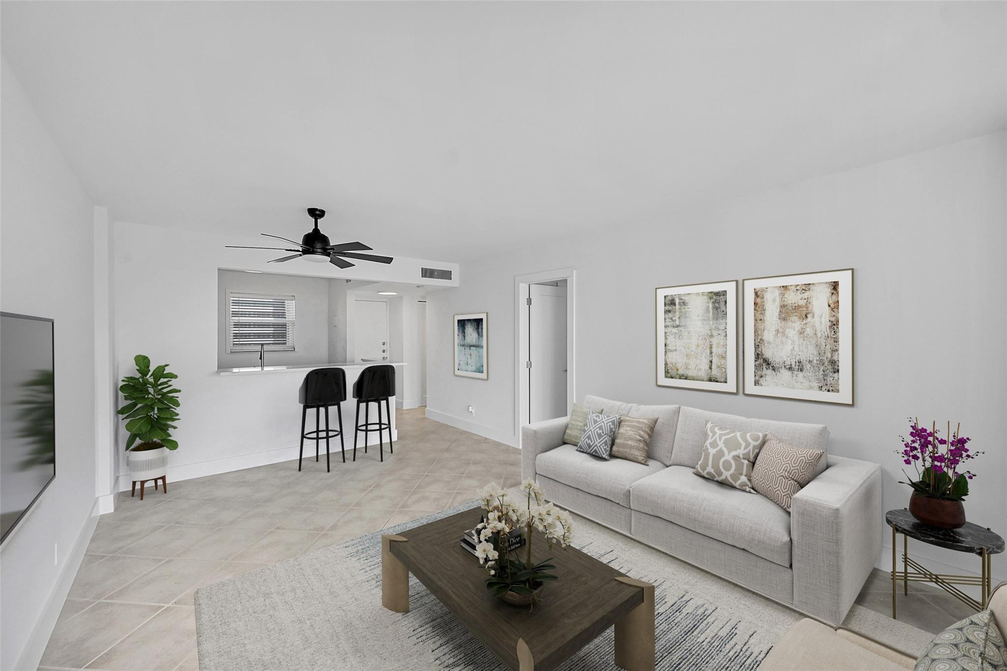 Open-plan living room with a gray sofa, dark coffee table, and breakfast bar with two stools.