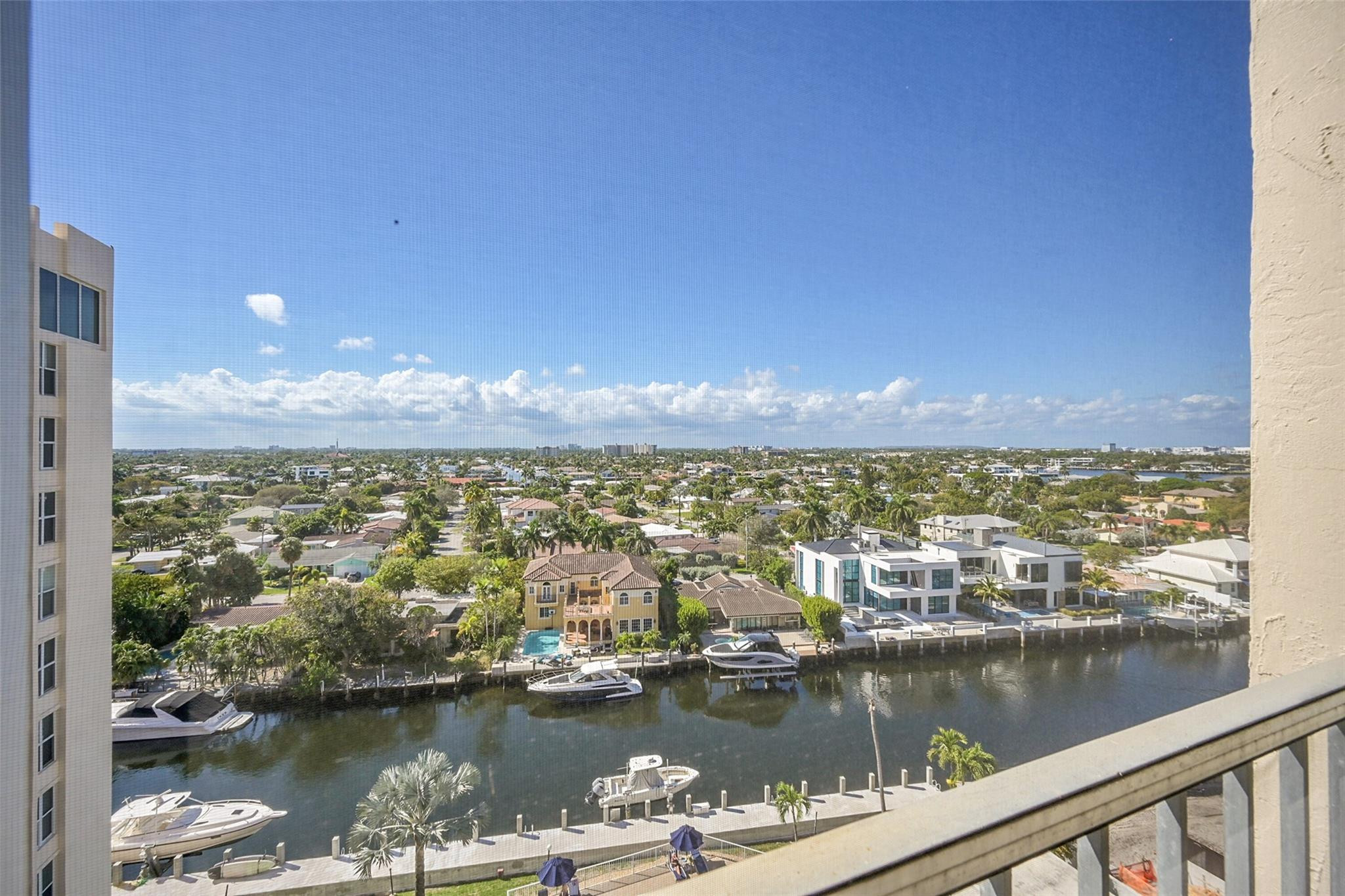 Balcony view over a canal lined with waterfront homes, docks, and boats.