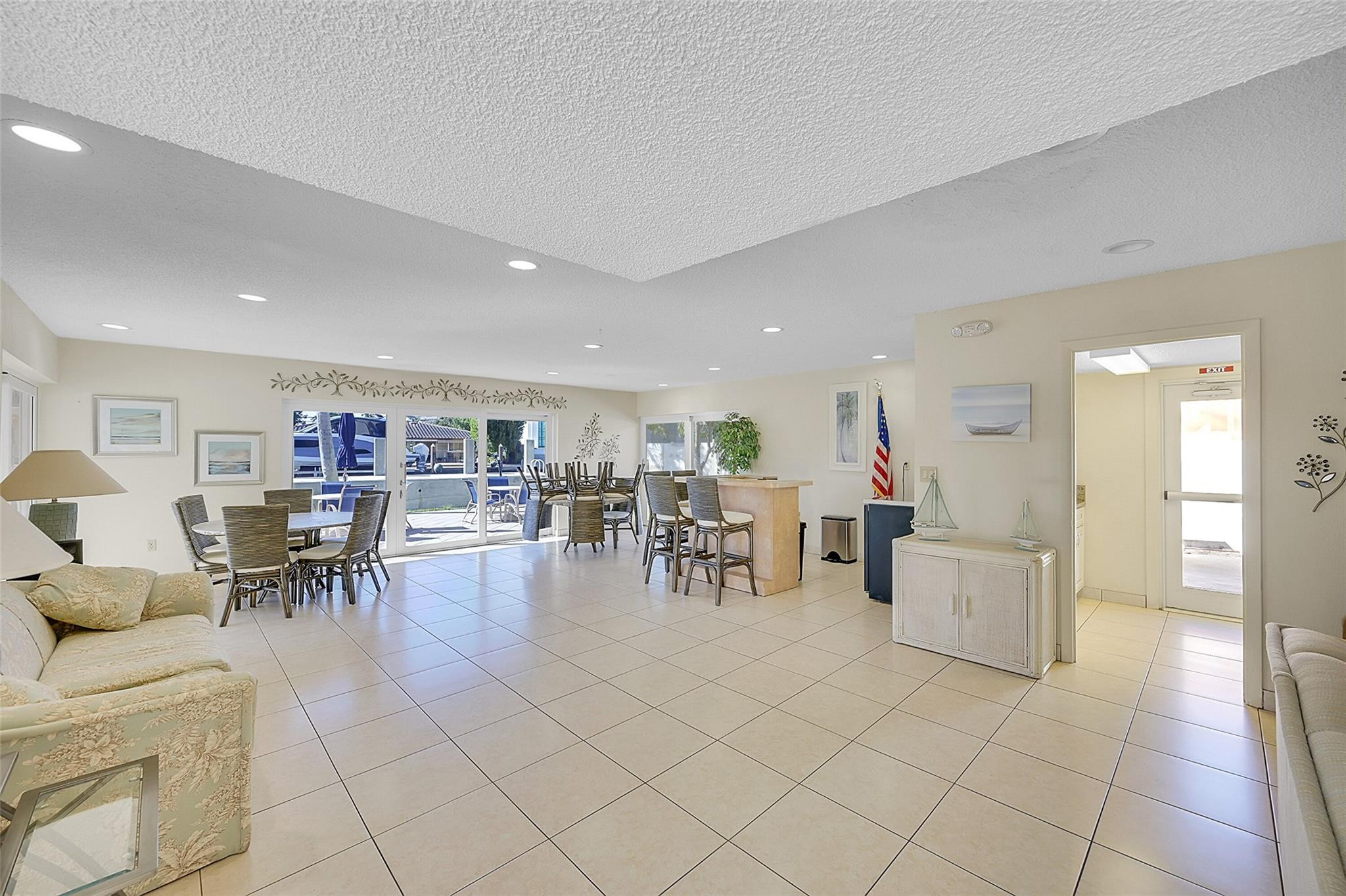 Furnished communal dining room with tiled floors and sliding doors opening onto a poolside patio.