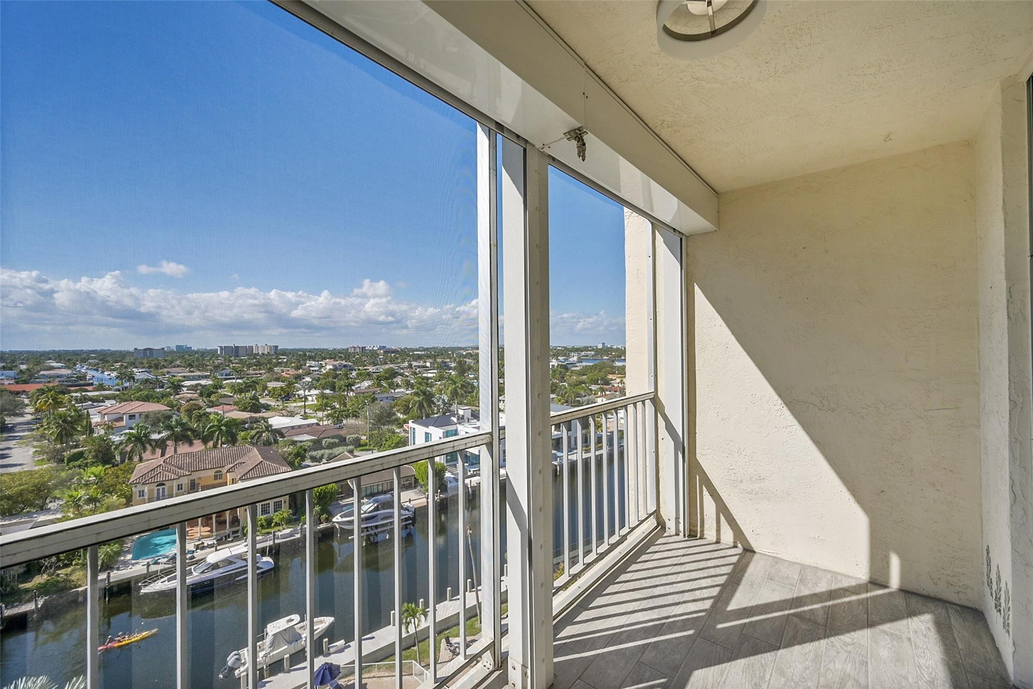 Condo balcony overlooking a canal with boats and palm-lined homes.