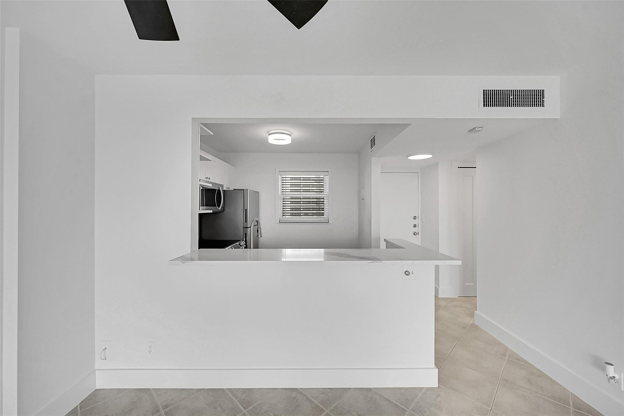 Kitchen with a stone breakfast bar, stainless steel appliances, and gray tile flooring.