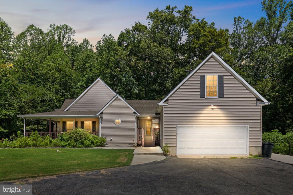 Gabled gray home with a covered porch and attached two-car garage, photographed at dusk.