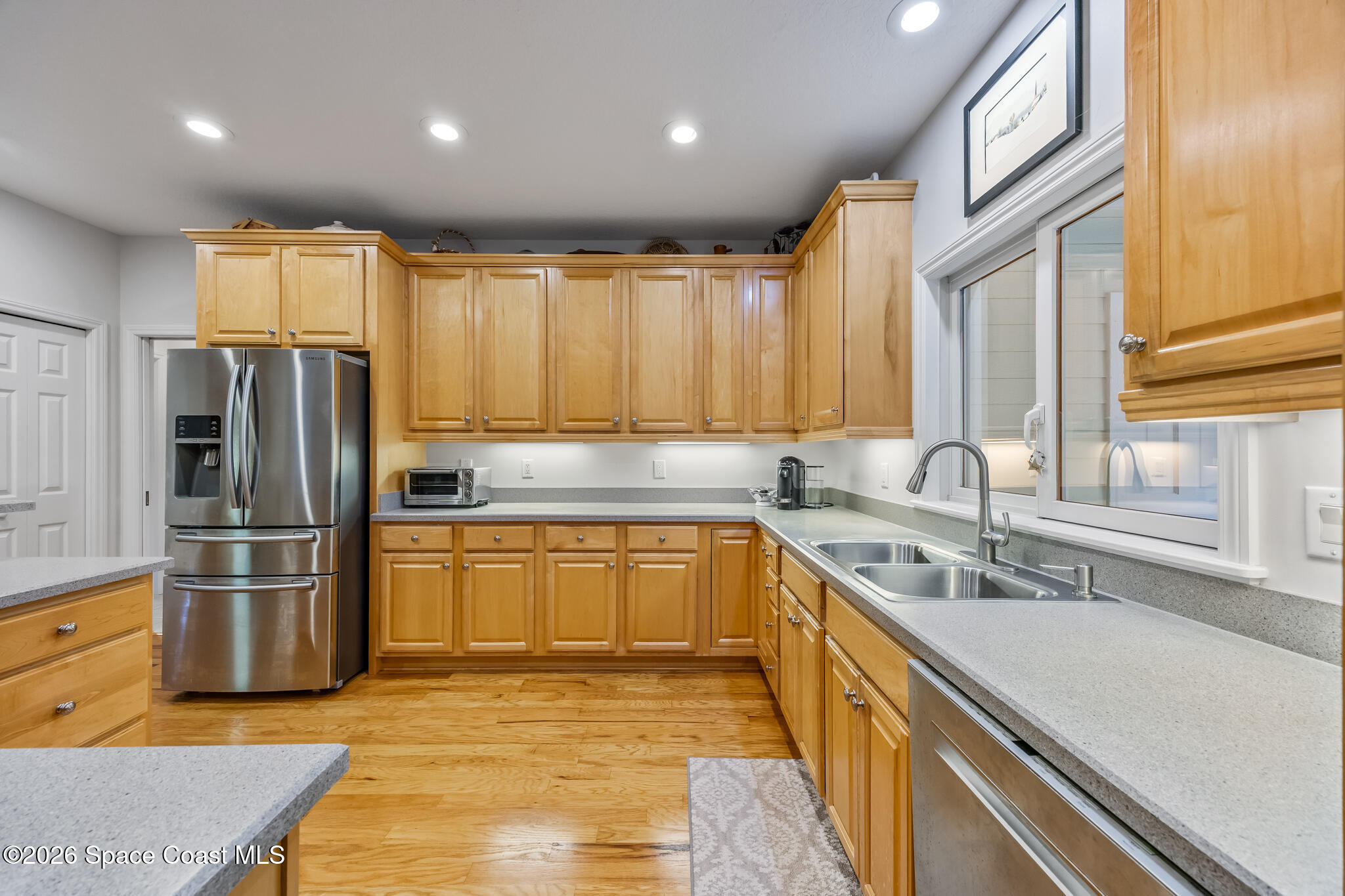 Kitchen with honey-colored cabinets, gray counters, stainless steel appliances, and a double-basin sink.