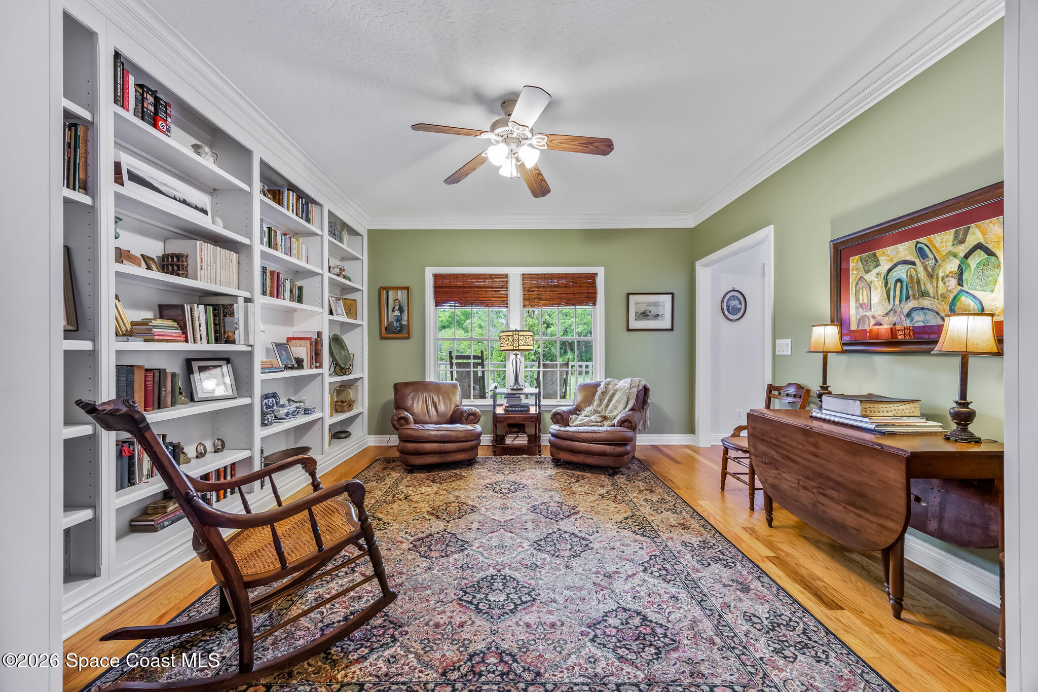 Furnished home library with built-in bookshelves, leather chairs, and a wooden desk.