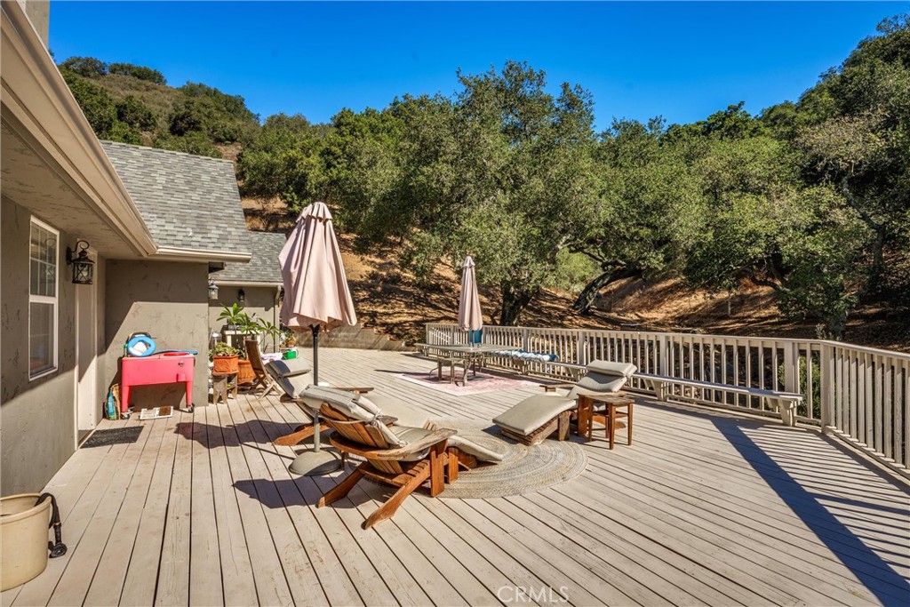 Wooden deck with lounge chairs and umbrellas overlooking a wooded hillside.