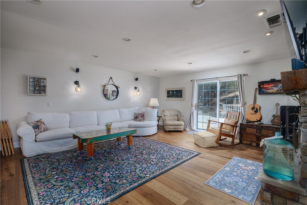 Living room with a white sectional, patterned rugs, wood floors, and sliding doors to a patio.