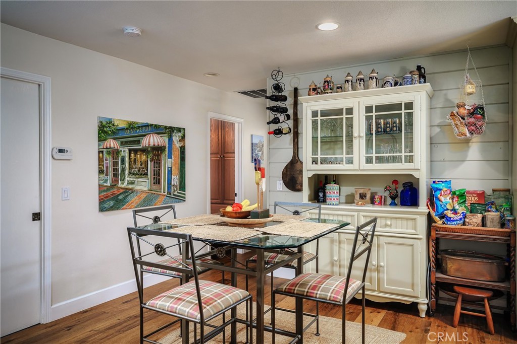 Dining area with a glass-top table, plaid chairs, and a white glass-front hutch.