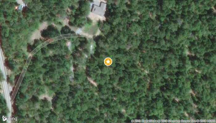 Aerial view of a wooded property marked with a yellow star, with a building and access road nearby.