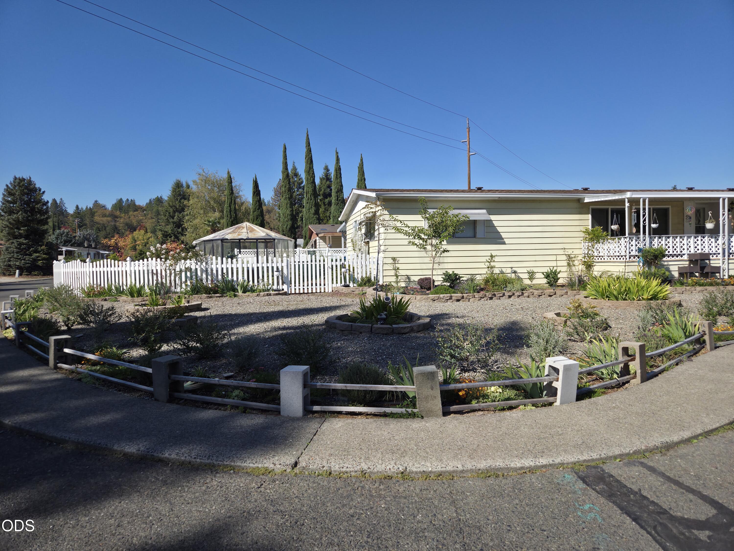 Single-story home with a white picket fence, landscaped gravel yard, and covered porch.
