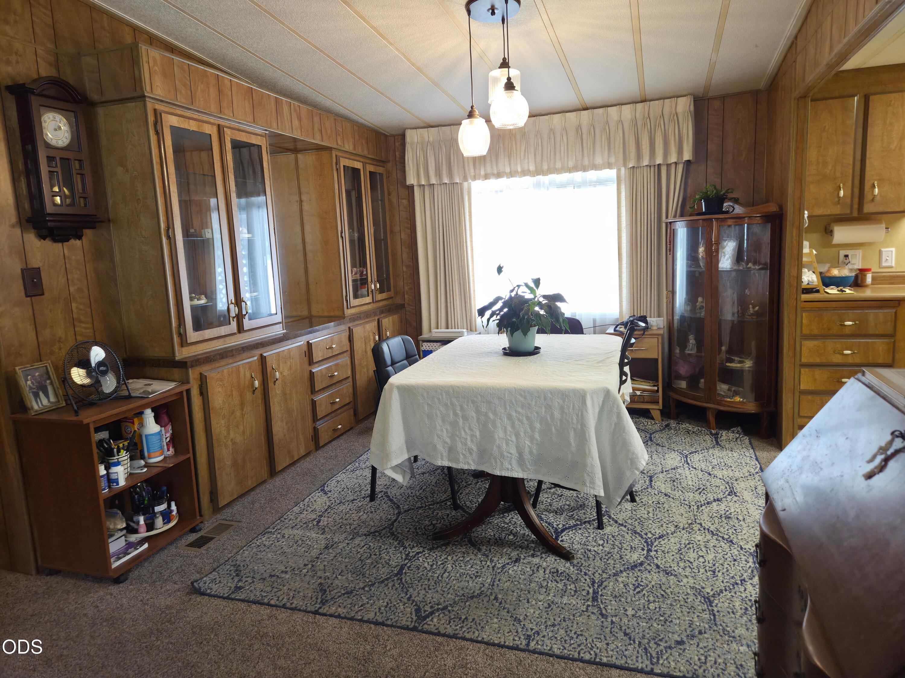 Dining room with extensive wood cabinetry, a covered table, and pendant lights.