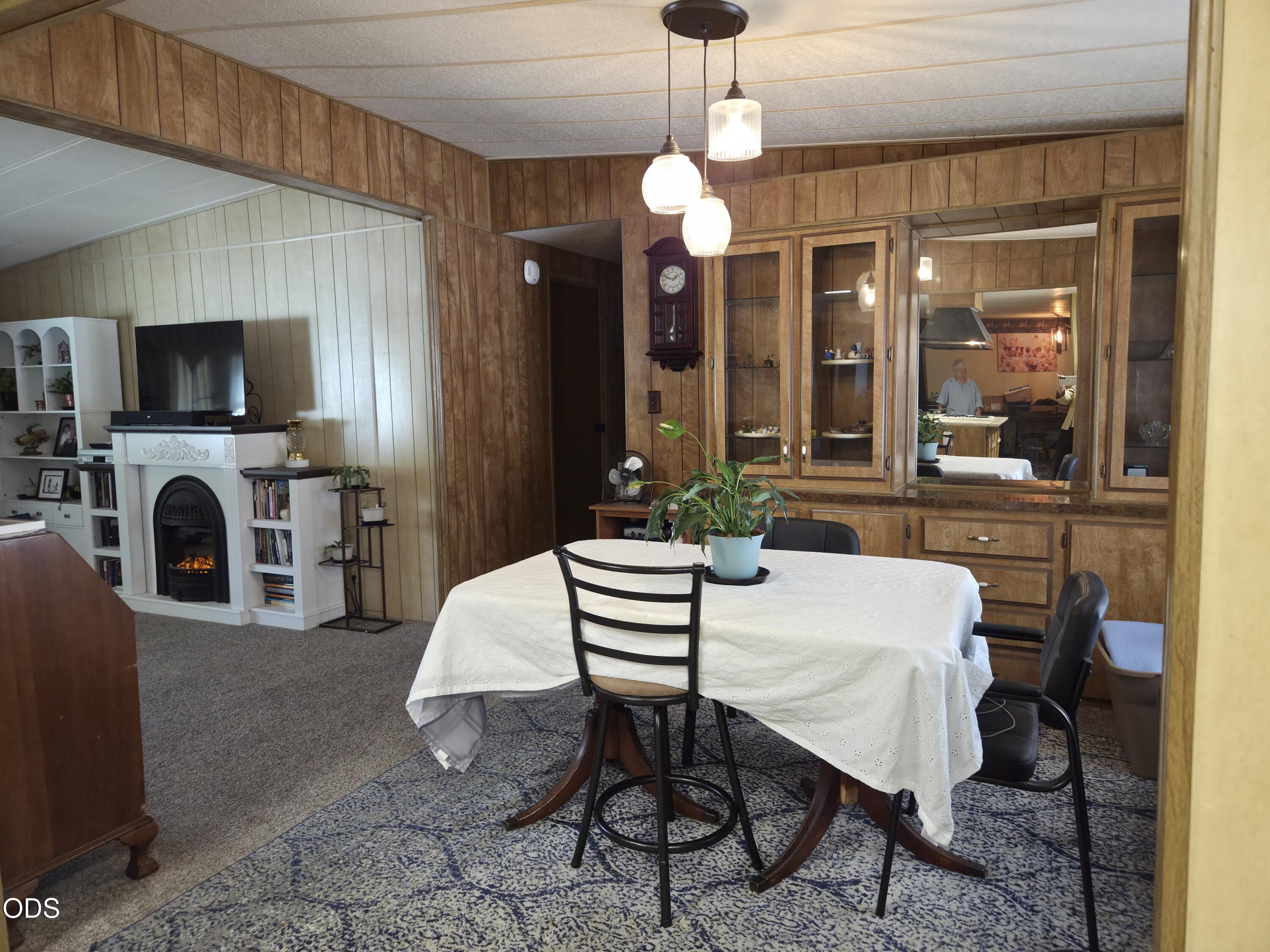 Dining room with a round table, wood-paneled cabinetry, and a white fireplace.