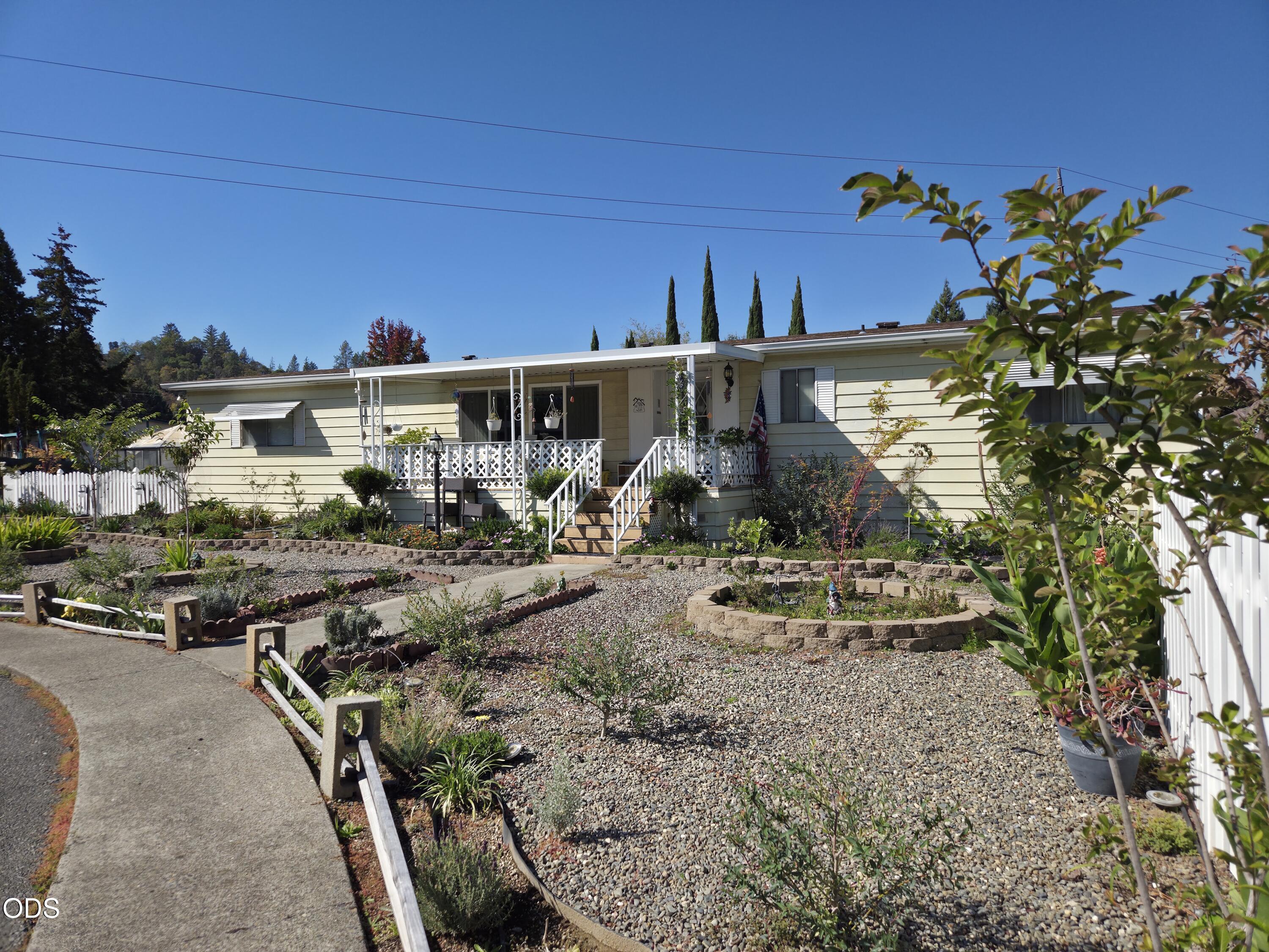 Single-story home with a covered white-railed porch and landscaped gravel front yard.