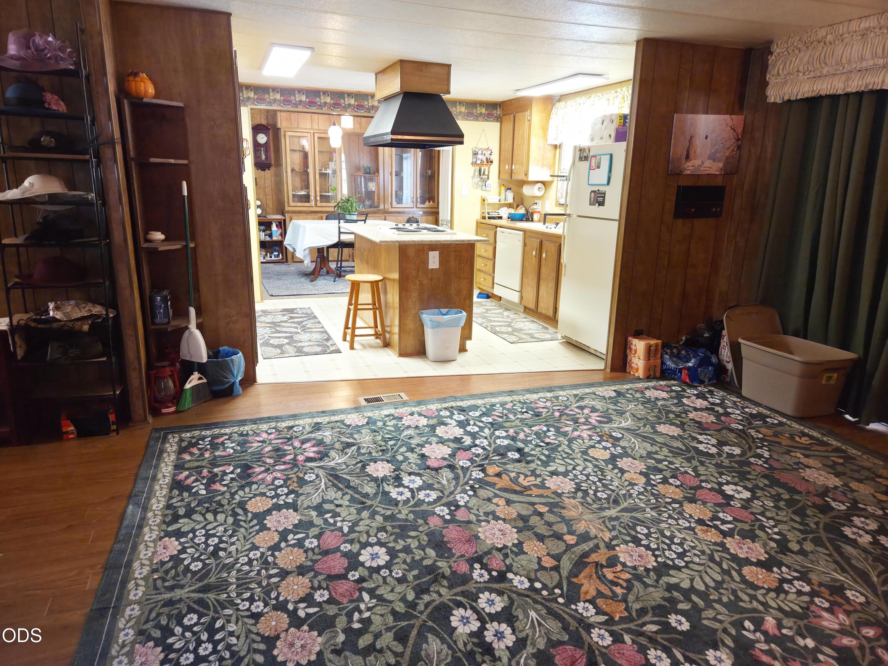 Kitchen with a central island, dark wood cabinetry, and a large floral rug in the foreground.