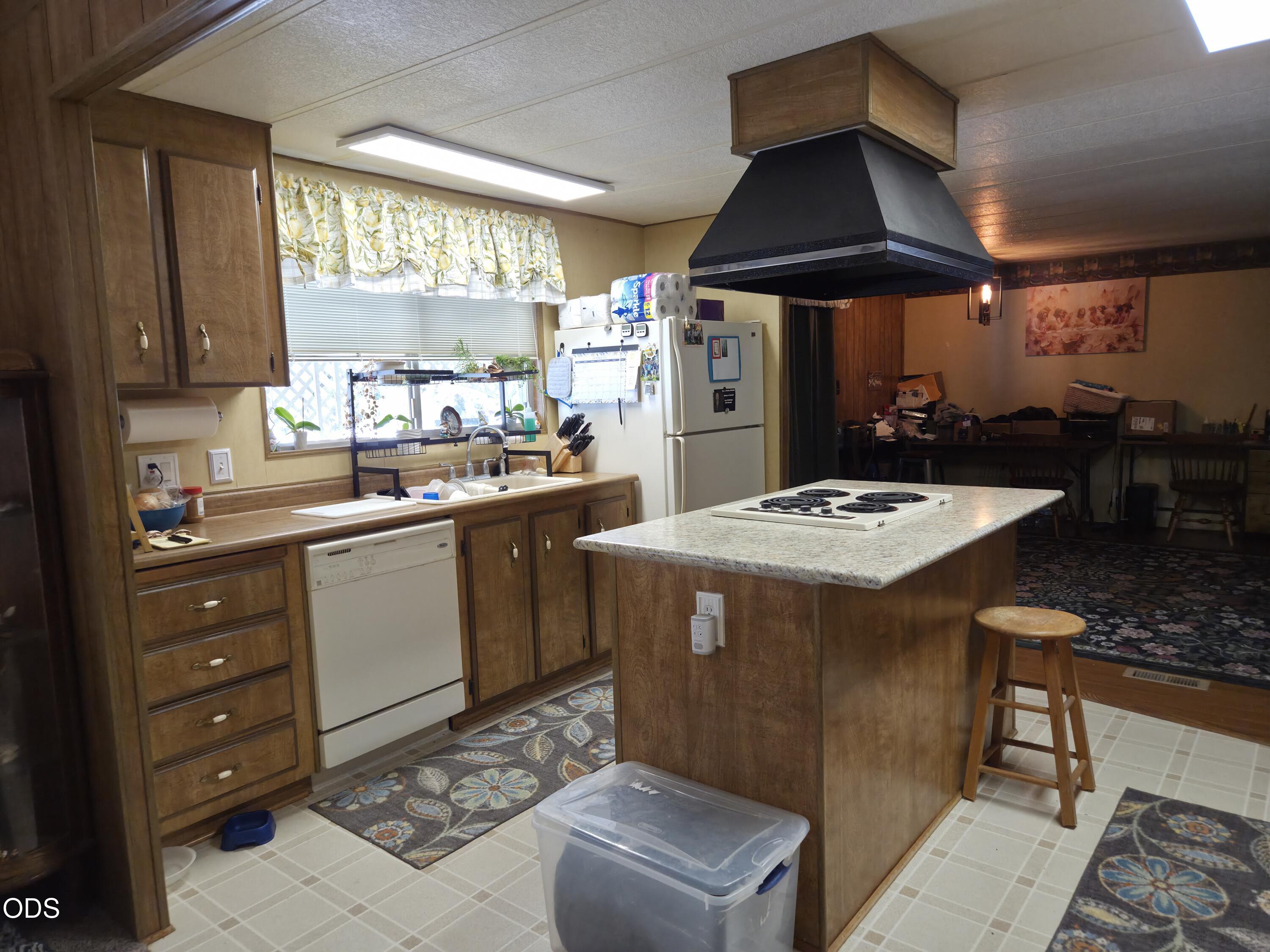 Kitchen with wood cabinetry, central island cooktop, and adjoining dining area.