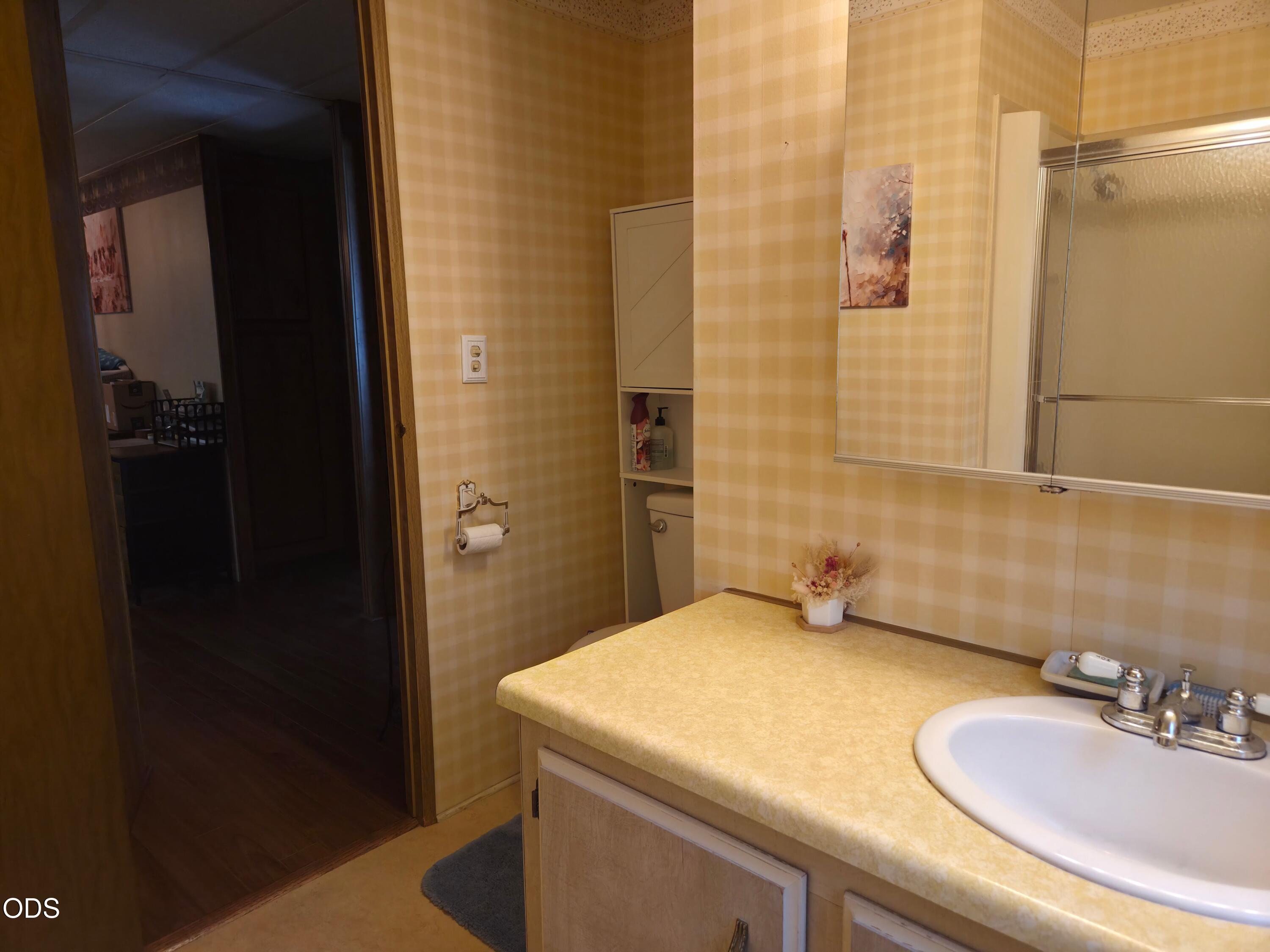 Bathroom with a yellow countertop, oval sink, mirrored cabinet, and frosted-glass shower.
