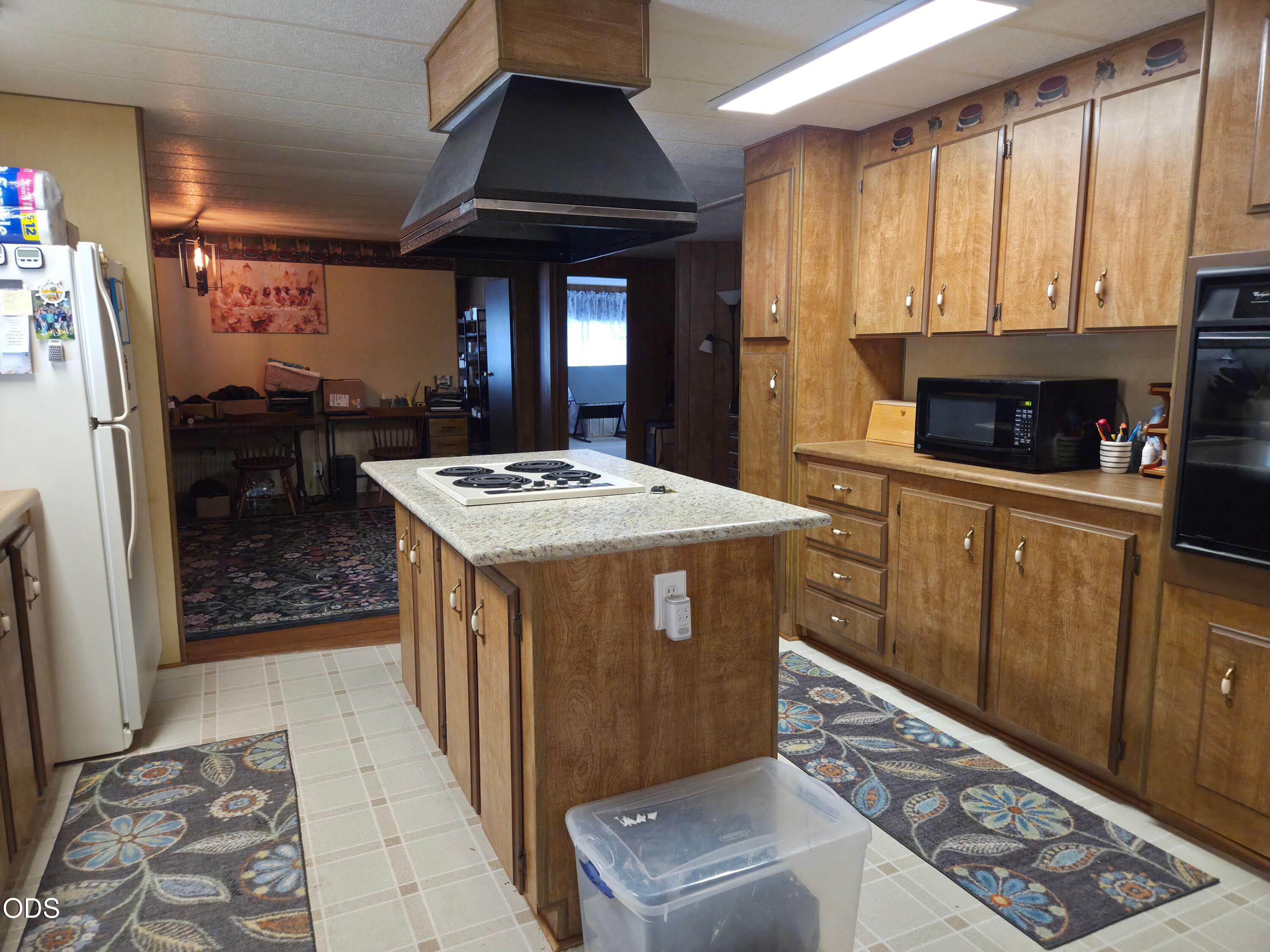 Kitchen with extensive wood cabinetry, a central cooktop island, and patterned floor runners.