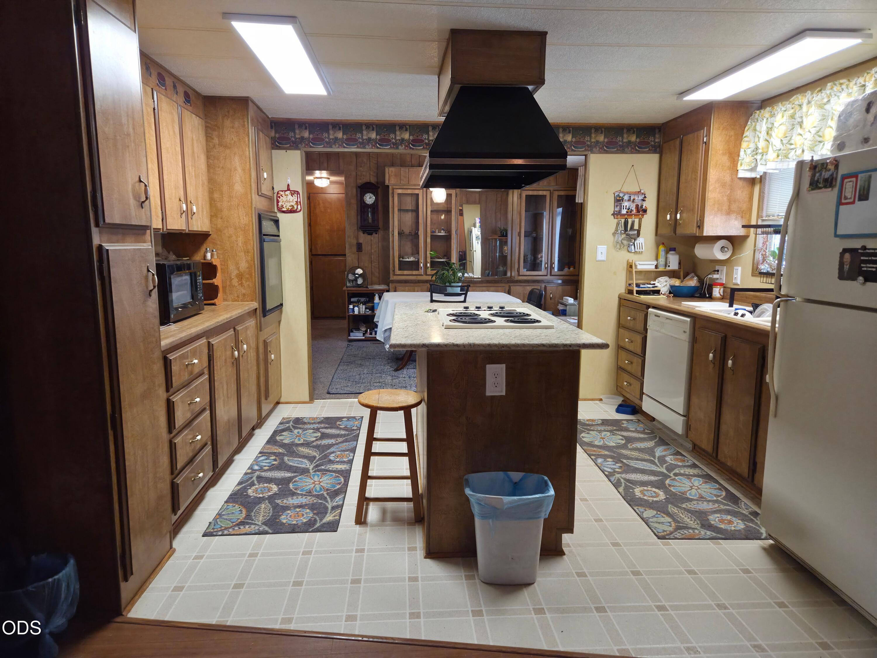 Kitchen with wood cabinets, a central island cooktop, and patterned floor runners.