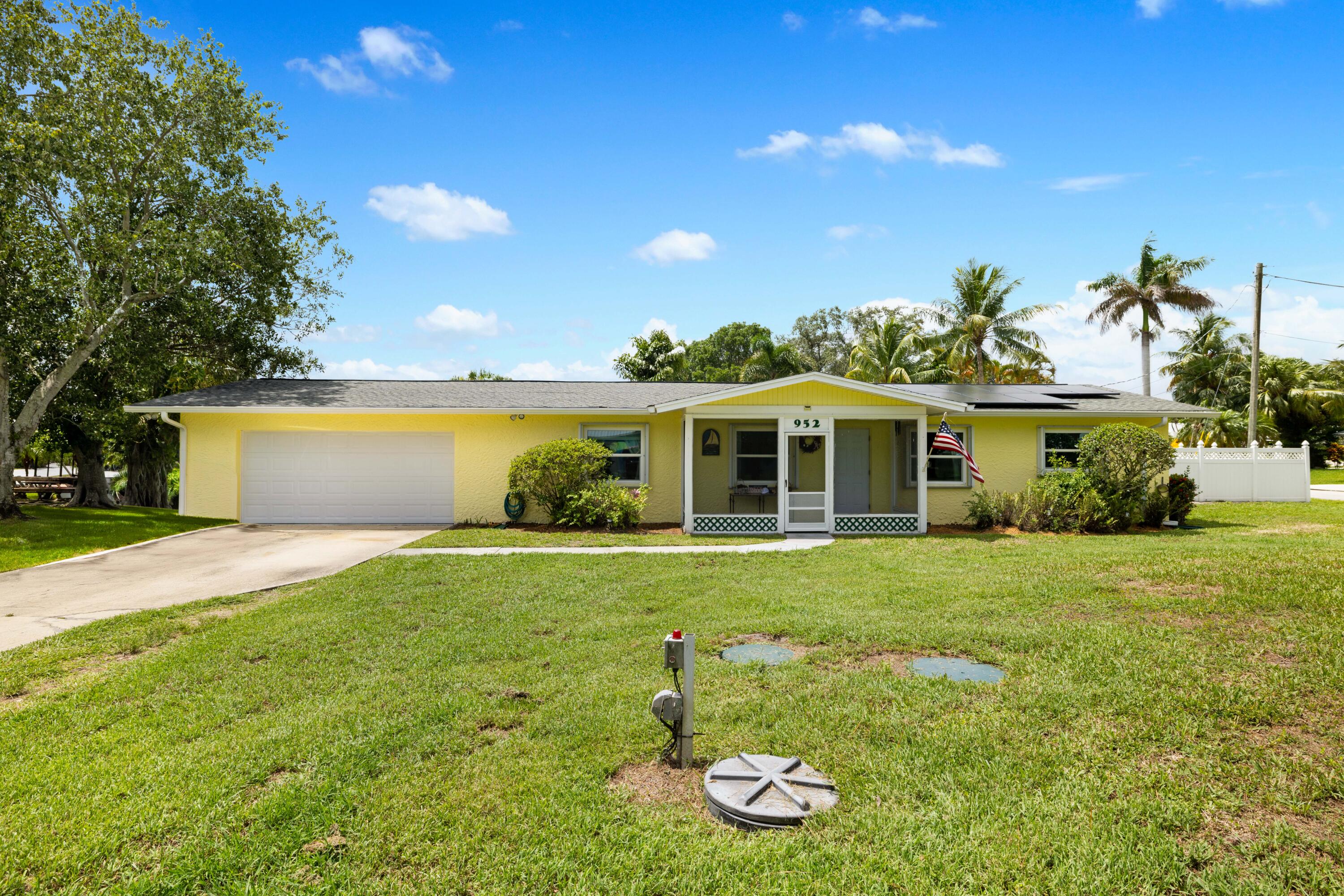 Yellow single-story house with a white garage, solar panels, and a covered front entry.
