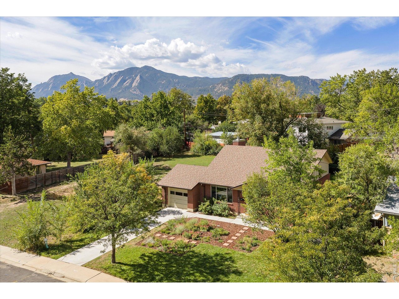 Aerial view of a brick home with a landscaped yard and mountain views.
