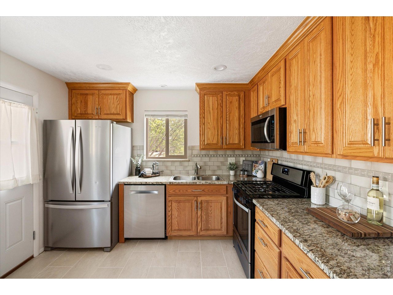 Kitchen with honey-toned wood cabinets, granite counters, and stainless steel appliances.