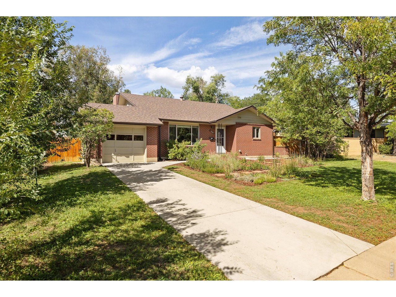 Single-story brick house with an attached garage, wide driveway, and landscaped front yard.