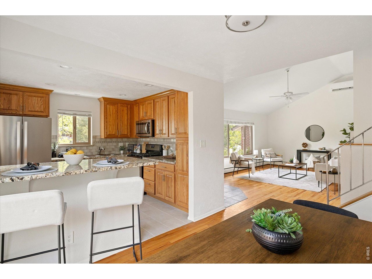 Open-plan kitchen and living room with wood cabinetry, granite counters, and a furnished sitting area.