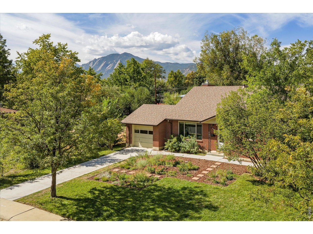 Brick home with an attached garage, landscaped yard, and mountain views.