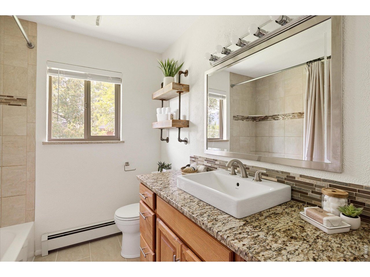 Bathroom with a granite vanity, vessel sink, large mirror, and tiled tub and shower.