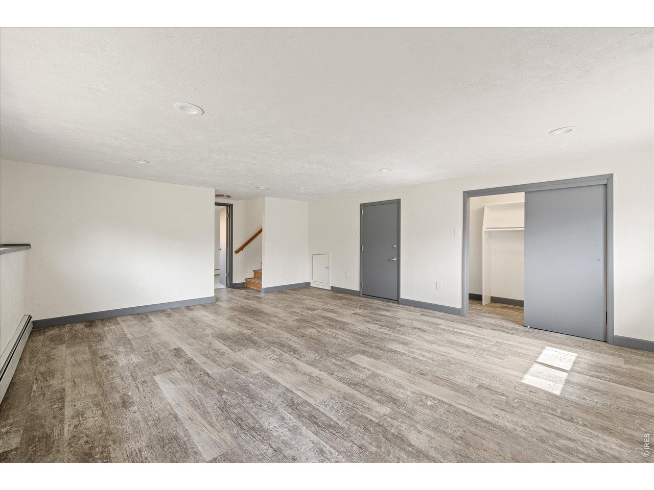 Vacant finished room with gray wood-look flooring, a sliding closet door, and stairs.
