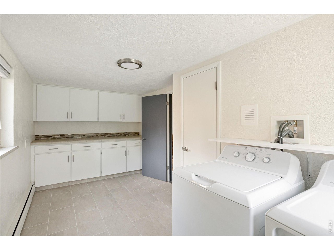 Laundry room with white cabinets, tiled floor, and a top-load washer and dryer.