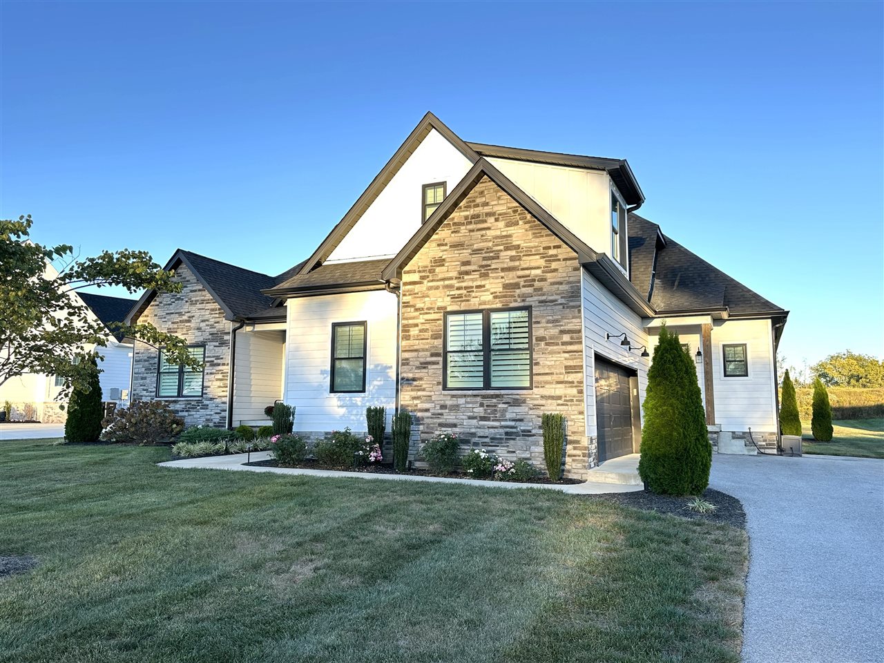 Modern home with stone facade, white siding, attached garage, and landscaped lawn.