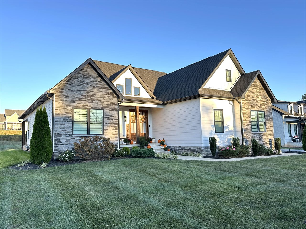 Home exterior with stone accents, white siding, and pumpkins on the front porch.
